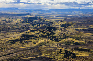 Dramatic iceland landscape of Craters of Laki volcanic fissure with a green hill and black lava looks like a moon.