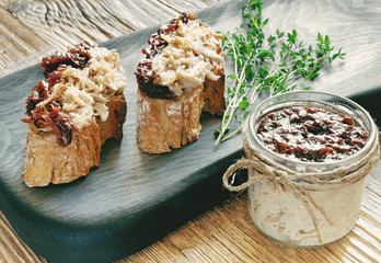 pulled pork covered with red onion confiture in a glass jar with the pork sandwiches on a black serving board decorated with fresh thyme