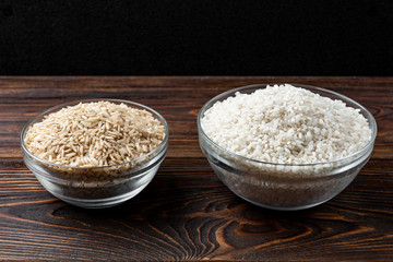 White and brown rice on dark wooden background.