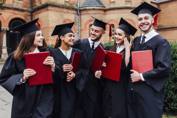 Graduates embrace, enjoy and look at the camera on the graduation ceremony!