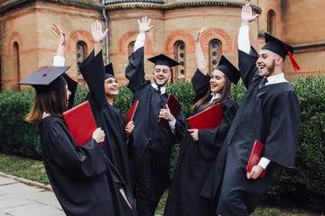 happy college graduate show diplomas at ceremony outside university!