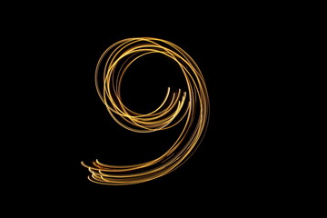 Long exposure, light painting photography.  Single number in a vibrant neon metallic yellow gold colour against a black background - obrazy, fototapety, plakaty