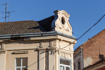 Side corner rooftop of old historic building with windows and antennas against blue sky