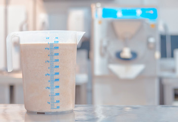 Gelato preparation bucket of hazelnut ice cream with ice cream machine in the background