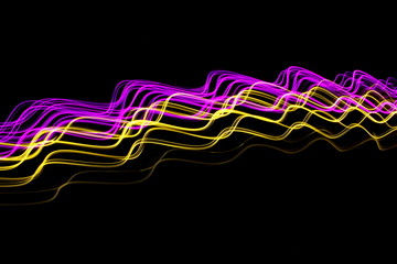 Long exposure, light painting photography.  Vibrant neon streaks of colour against a black background