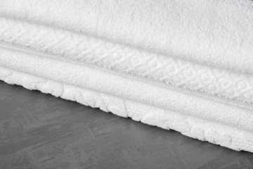 a soft folded bath towel on the gray surface, close-up