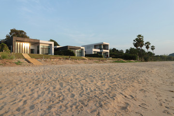 Front view of house on the beach and a setting sun, real estate