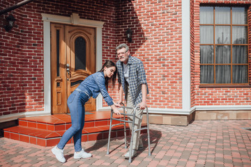 Young woman halping her uncle with wheelchair near nursing home!