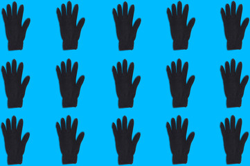 Horizontal rows of black warm woolen gloves on blue background. Seamless pattern. Top view