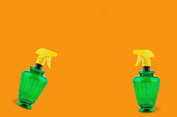 Pair of plastic sprayers on orange background with copy space for your text