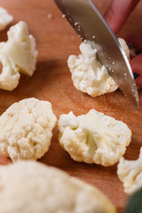 young woman in a gray aprons cuts cauliflower broccoli
