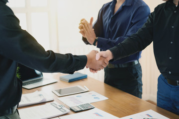 Businessman stand handshake and clapping of appreciation about the success of business at meeting.