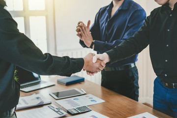 Businessman stand handshake and clapping of appreciation about the success of business at meeting.