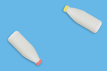 Fresh dairy product in two full plastic bottles for milk, kefir or yoghurt with red and yellow caps on blue table on kitchen. Copy space for your text. Top view. Cooking concept