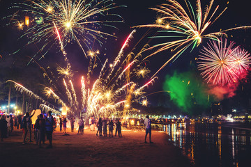 Fireworks with silhouettes of people in a holiday events.New Year fireworks on the beach. Travelers...