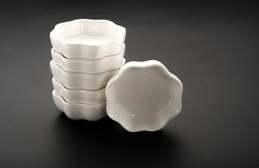 flower shape empty ceramic dishes stack up on a black background