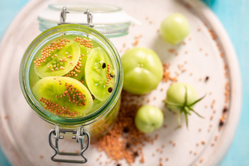 Closeup of natural pickled green tomatoes on blue table