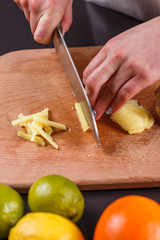 young woman in a gray aprons cuts the root of ginger