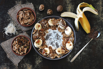 Healthy breakfast bowl with yogurt and chia, cereal, raisins, banana, walnut and seeds. Superfoods Energy food. Keto diet.