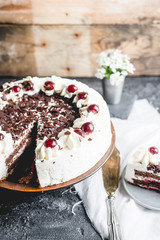 German, delicious Black Forest cake, with a delicate white cream, cherries in alcohol and dark chocolate on a dark stone table decorated with white linen fabric