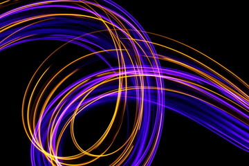Long exposure, light painting photography.  Vibrant loops and streaks of neon purple and metallic gold color against a black background.