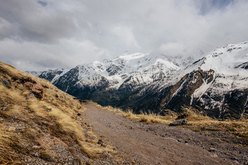 snow-capped mountains against a cloudy sky and a trail