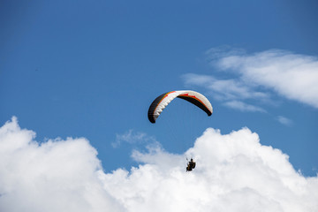 Paraglider flying in cloudy sky