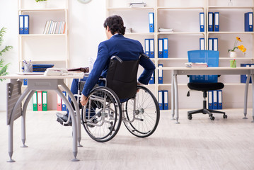 Young male employee in wheelchair working in the office 