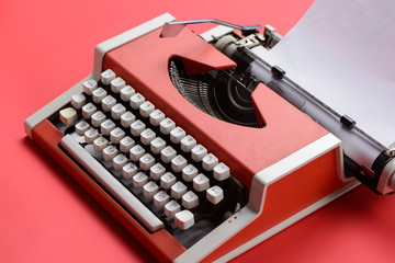 Closeup of red vintage typewriter with white blank paper sheet
