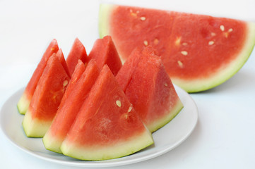 Red watermelon slices on white plate over white background, selective focus
