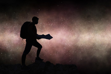 Fototapeta na wymiar Silhouette travelling backpacker holding map on rocky mountain against milky way galaxy background