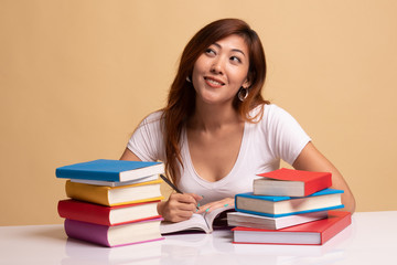 Young Asian woman read a book with books on table.