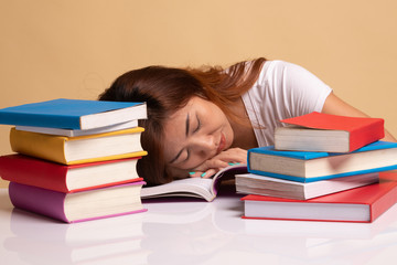 Exhausted Young Asian woman sleep with books on table.