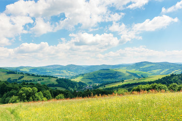beautiful summer countryside in mountains. wonderful sunny day scenery. grassy rural fields and meadows with wild herbs. hills and mountains in the distance. blue sky with fluffy clouds
