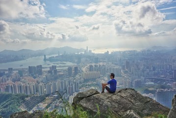 active lifestyle hiker on the top of mountain overlooking city skyscrapers in hong kong...