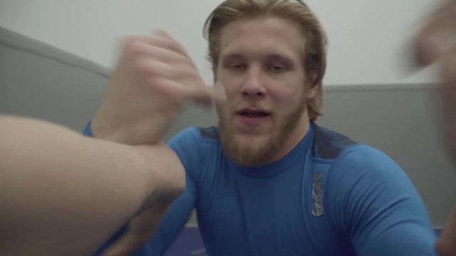 Funny blond bearded man wrestling with another guy, trying to grab his hands in the gym close up. Two athletes fooling around in training. First person shooting