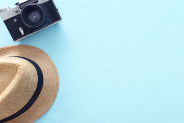 Top view photo of traveling concept with fedora hat and photo camera over blue background