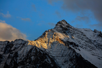 Epic snow mountains, snow covered mountain range - Daocheng Yading Nature Reserve. Ganzi, Garze, Kham Tibetan area of Sichuan Province China. Dramatic lighting during sunset, Clouds and Sky