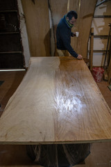 Craftsman carpenter working in his studio giving oil to a chestnut wood board.