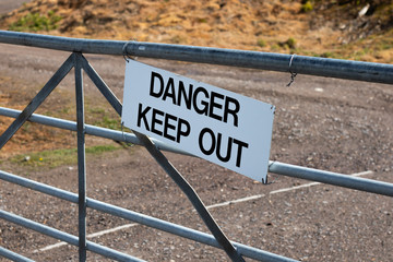 Danger keep out sign on metal gate boundary to disused contaminated factory site