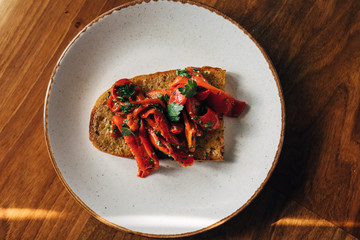 Roasted red peppers on a toasted bread with parsley and olive oil served on a plate