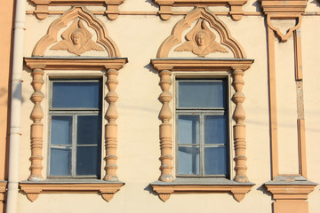 Two windows on beige building wall of classical house. Architecture detail of ornamental historic facade exterior