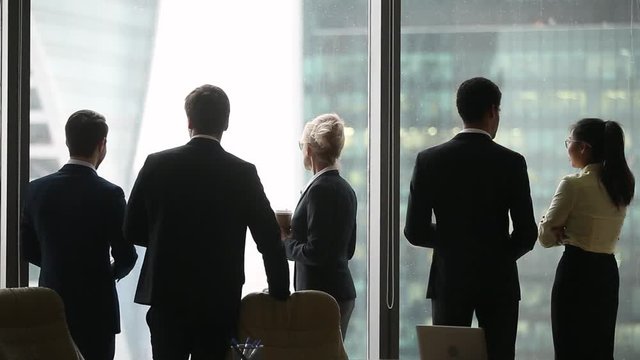 Rear back view of diverse colleagues group talking at work