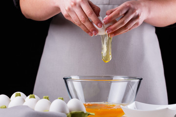 young woman in a gray aprons breaks the eggs