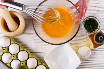 young woman in a gray aprons breaks the eggs