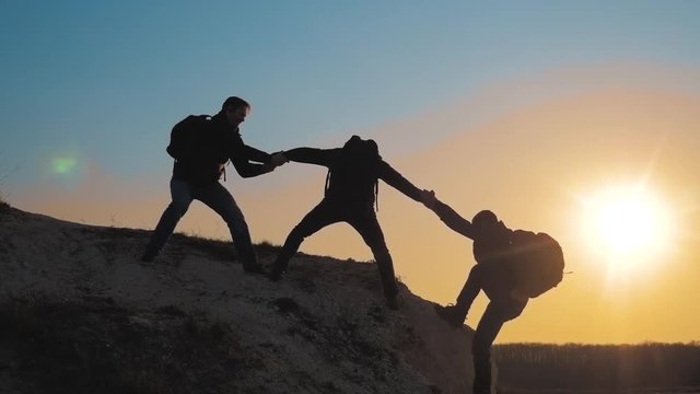 teamwork help lifestyle business travel silhouette concept. group of tourists lends a helping hand climb the cliffs mountains. people climbers climb to the top overcoming hardships the path to victory