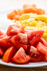 Sliced tomatoes and corn on white plate