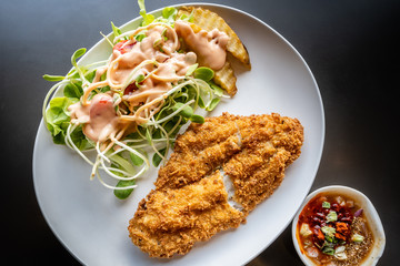 fried fish and salad on white plate, top view
