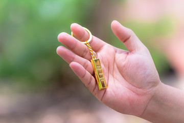 Man hand holding golden key with golden bar with blurred nature background.