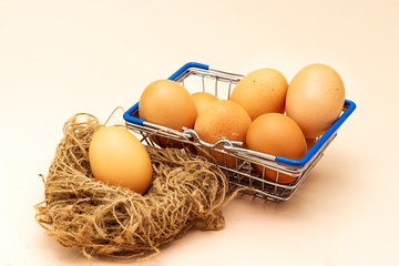 some organic egg  in metal shopping basket and some on nest isolated on pink background